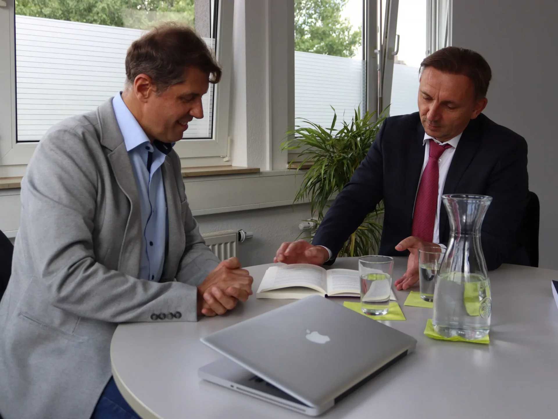 Drei Personen in Businesskleidung beraten sich am Schreibtisch